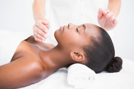 Woman on massage couch with white towels receiving Reiki